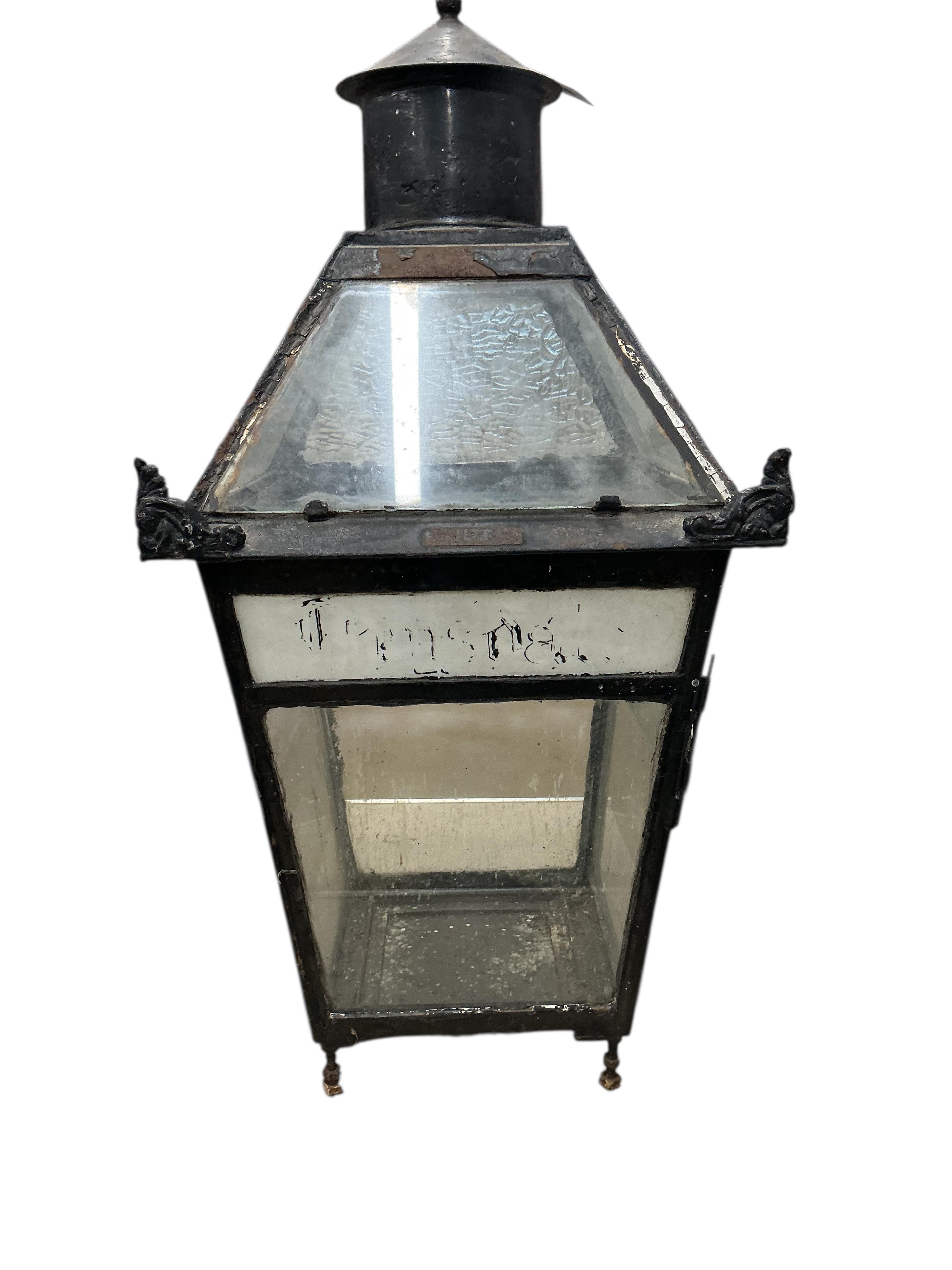 A glass and steel railway station lantern with an opaque glass panel showing the remains of a painted possible station name, missing the burner etc., 80cm high, 40cm wide